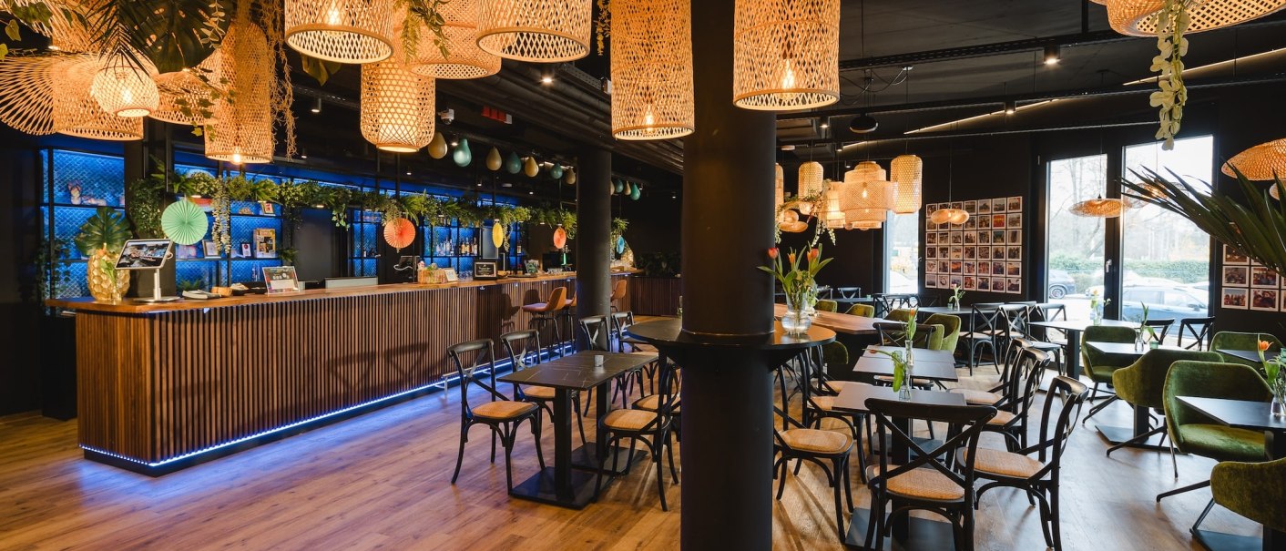 Ein stilvoll eingerichtetes Café mit hölzernem Boden, modernen Möbeln und dekorativen Lampen., © TOMAS