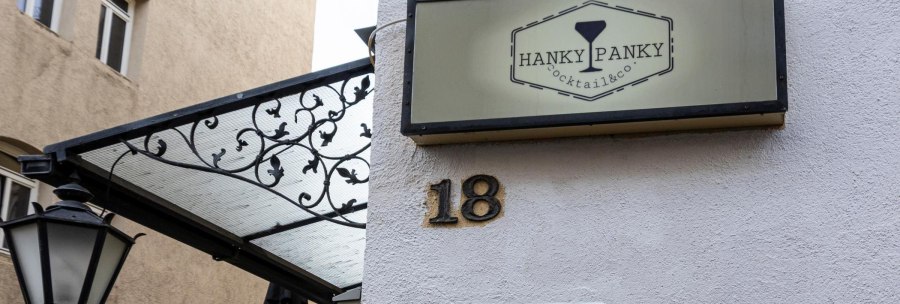 Ein Schild mit der Aufschrift 'Hanky Panky Cocktail & co' h&auml;ngt an einer Hauswand neben der Hausnummer 18. Eine Laterne und ein dekoratives Vordach sind sichtbar., &copy; Stuttgart-Marketing GmbH, Sarah Schmid