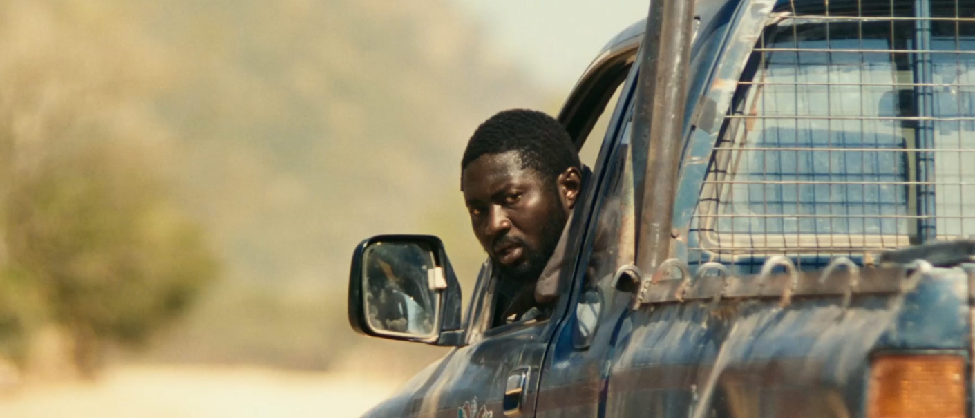 Ein Mann schaut aus dem Fenster eines blauen Pick-up-Trucks in einer ländlichen Umgebung., © Sic Productions