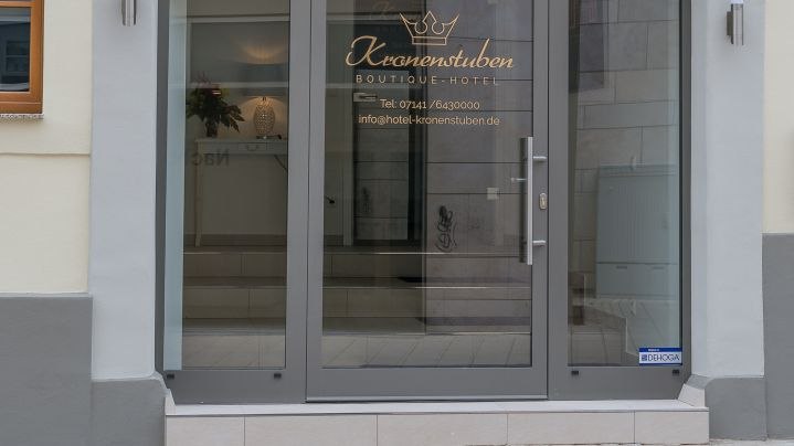 Glastür eines Boutique-Hotels mit dem Schriftzug 'Kronenstuben' und Kontaktinformationen., © Kronenstuben Boutique-Hotel