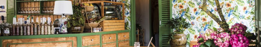 Gemütlicher Gastraum mit Holzmöbeln, bunten Blumen, Regalen voller Flaschen und Büchern. Helle Lampen und florale Tapete schaffen eine einladende Atmosphäre., © Vietal Kitchen Gemütlicher Gastraum mit Holzmöbeln, bunten Blumen, Regalen voller Flaschen und Büchern. Helle Lampen und florale Tapete schaffen eine einladende Atmosphäre., © Vietal Kitchen