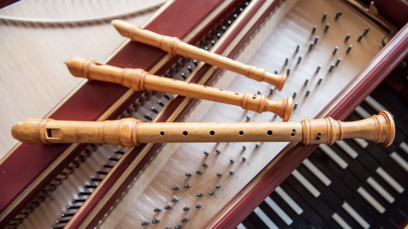 Drei hölzerne Blockflöten liegen auf den Saiten eines geöffneten Cembalos. Die Flöten sind parallel angeordnet., © Jens Volle