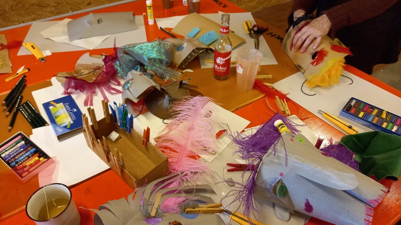 Ein Tisch mit Bastelmaterialien, Masken und Getr&auml;nken in einem kreativen Workshop. Verschiedene Farben und Texturen sind zu sehen., &copy; KVWH