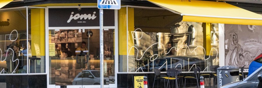 Schaufenster des Deli mit gelben Markisen. &Uuml;ber der T&uuml;r am Eck des Geb&auml;udes steht "jomi Bagel Deli"., &copy; Stuttgart-Marketing GmbH, Sarah Schmid
