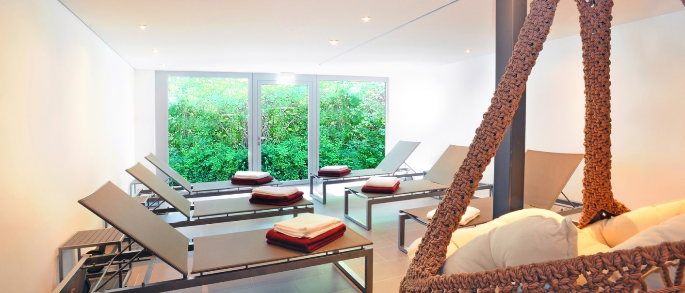 Moderner Wellnessbereich mit Liegen, Hängesessel und großen Fenstern mit Blick ins Grüne., © Schlosshotel Monrepos Moderner Wellnessbereich mit Liegen, Hängesessel und großen Fenstern mit Blick ins Grüne., © Schlosshotel Monrepos