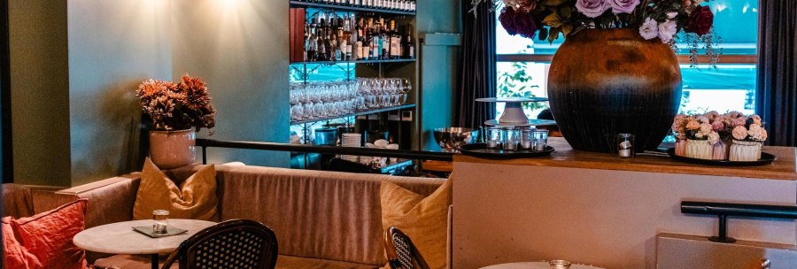 Gem&uuml;tliches Caf&eacute; mit Sofas, runden Tischen und Blumenarrangements. Im Hintergrund Weinflaschen und Gl&auml;serregale., &copy; Stuttgart Marketing GmbH - Sarah Schmid