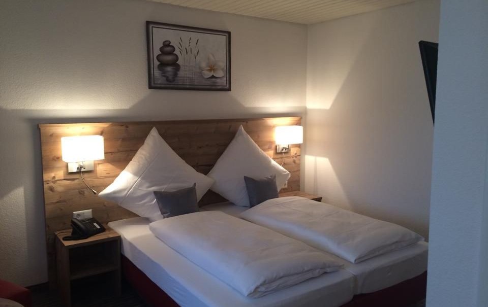 Cozy double room with wooden headboard, two pillows, two bedside tables and a picture on the wall., &copy; Hotel Lamm Hegnach
