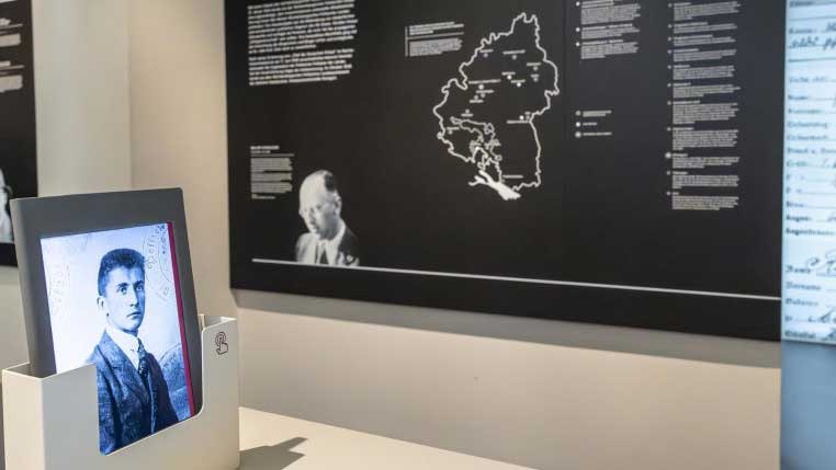 Ein historisches Foto in einem Ausstellungsraum, im Hintergrund eine Karte und Texttafeln an der Wand., © Haus der Geschichte Baden-Württemberg Ein historisches Foto in einem Ausstellungsraum, im Hintergrund eine Karte und Texttafeln an der Wand., © Haus der Geschichte Baden-Württemberg