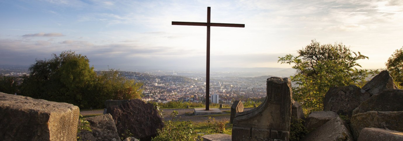 Ein Kreuz auf dem Birkenkopf in Stuttgart, umgeben von Tr&uuml;mmern, mit Blick auf die Stadt im Hintergrund bei Sonnenuntergang., &copy; Stuttgart-Marketing GmbH, Jean-Claude Winkler