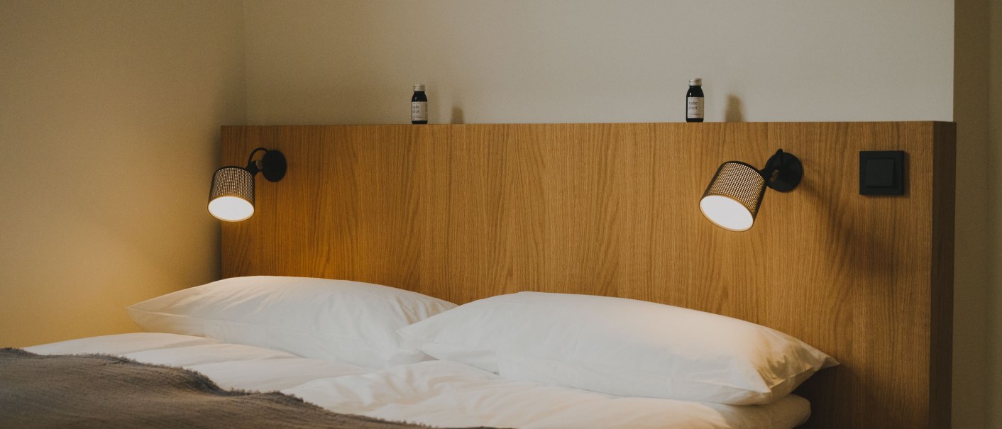 Doppelbett mit Holzr&uuml;ckwand, zwei Leselampen und kleinen Flaschen darauf. Schlichte, moderne Einrichtung., &copy; Peter Oliver Wolff / DAS EDITH