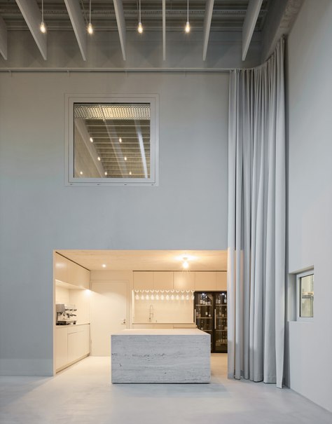 Eine moderne Küche mit hohen Decken, minimalistischer Einrichtung und einem zentralen Küchenblock. Große Vorhänge und dezente Beleuchtung ergänzen das Design., © club traube Eine moderne Küche mit hohen Decken, minimalistischer Einrichtung und einem zentralen Küchenblock. Große Vorhänge und dezente Beleuchtung ergänzen das Design., © club traube