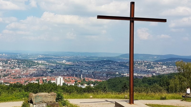 Blick vom Birkenkopf in Stuttgart mit einem großen Kreuz im Vordergrund und der Stadt im Hintergrund unter einem bewölkten Himmel., © Stuttgart-Marketing GmbH