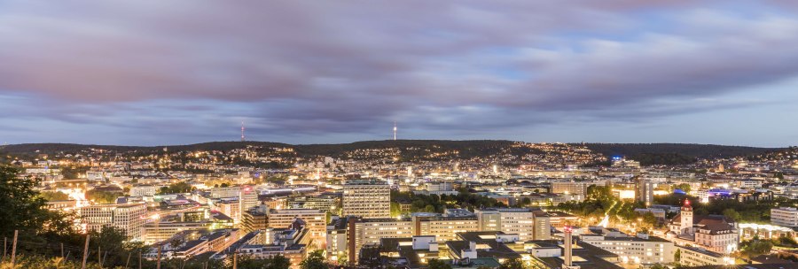 Panorama einer Stadt bei Abenddämmerung, mit beleuchteten Gebäuden und einem bewölkten Himmel im Hintergrund., © SMG, Werner Dieterich Panorama einer Stadt bei Abenddämmerung, mit beleuchteten Gebäuden und einem bewölkten Himmel im Hintergrund., © SMG, Werner Dieterich