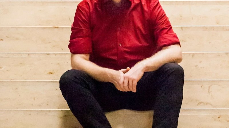 Eine Person in einem roten Hemd sitzt entspannt auf einer hellen Marmortreppe und schaut in die Kamera., &copy; Renitenztheater Stuttgart e.V.