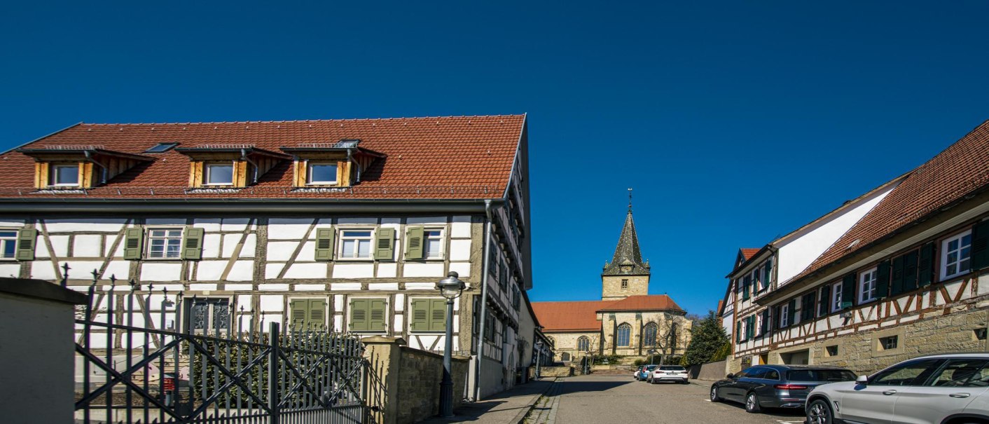 Half-timbered houses in Kornwestheim with a church in the background, under a clear blue sky., © SMG Stuttgart Marketing GmbH - Sarah Schmid