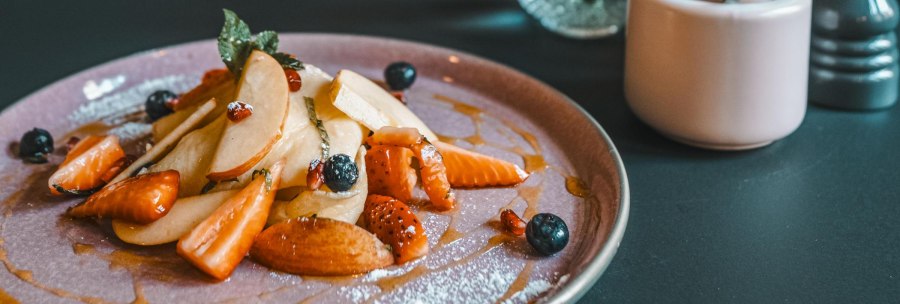 Ein Teller mit geschnittenen Fr&uuml;chten, Beeren und Sirup. Daneben eine Zuckerdose und ein Salzstreuer auf einem dunklen Tisch., &copy; Lupin, Stuttgart