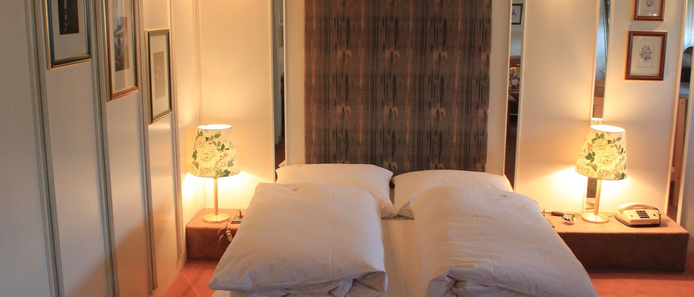 A cozy hotel room with a double bed, two bedside lamps, and decorative pictures on the wall., &copy; Hotel Spahr