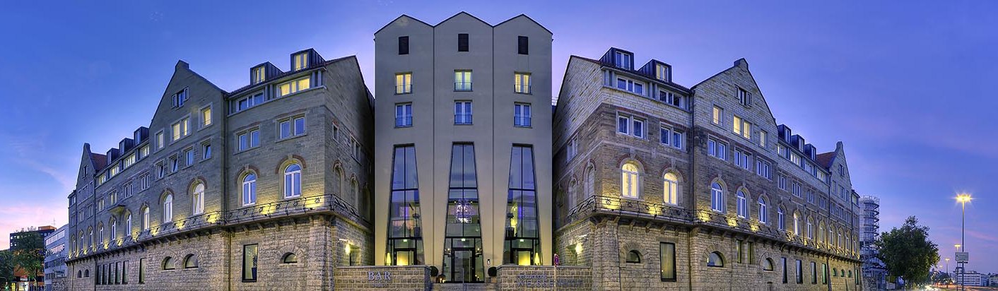 Das Arcotel Camino bei Dämmerung, mit beleuchteten Fenstern und einem klaren Himmel im Hintergrund. Historische Fassade mit modernen Elementen., © www.fnoxx.de Das Arcotel Camino bei Dämmerung, mit beleuchteten Fenstern und einem klaren Himmel im Hintergrund. Historische Fassade mit modernen Elementen., © www.fnoxx.de