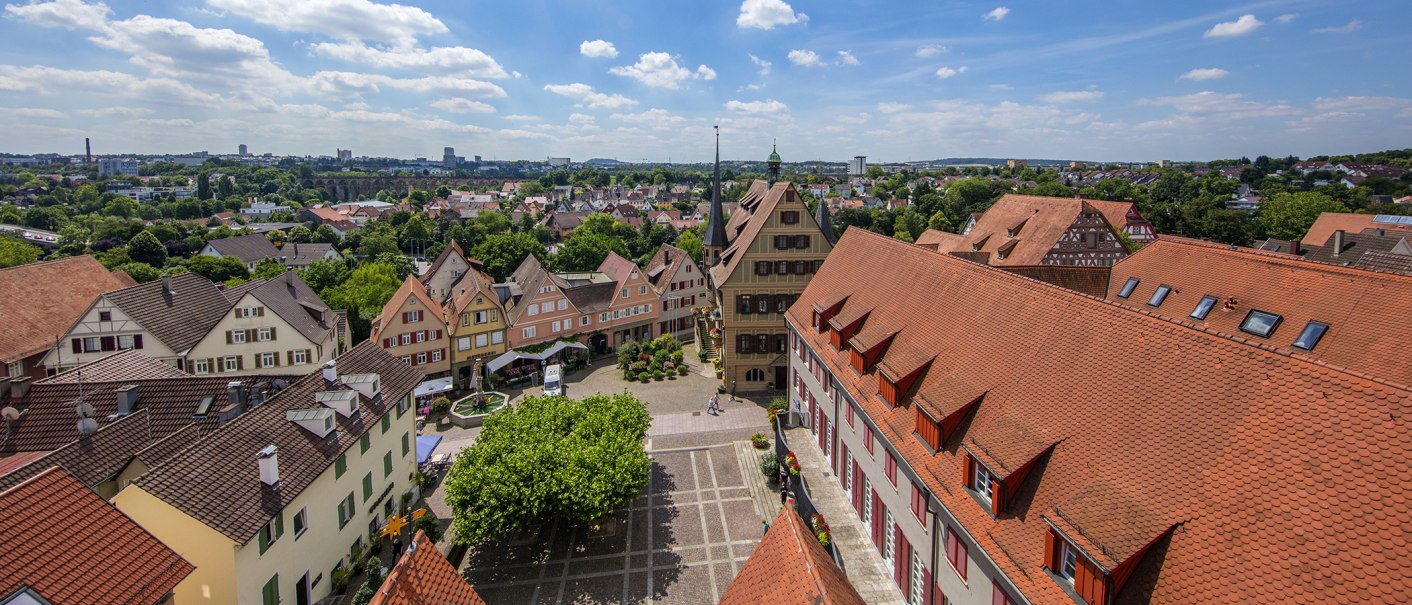 A panoramic view of Bietigheim-Bissingen with half-timbered houses, red-tiled roofs, and a central square, surrounded by green countryside and a blue sky., © Stuttgart-Marketing GmbH, Achim Mende A panoramic view of Bietigheim-Bissingen with half-timbered houses, red-tiled roofs, and a central square, surrounded by green countryside and a blue sky., © Stuttgart-Marketing GmbH, Achim Mende