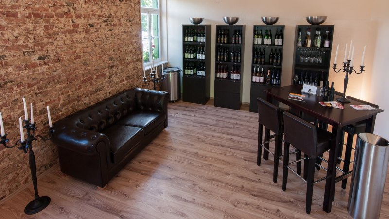 Gemütliche Vinothek mit Ledersofa, Weinregalen und Stehtisch. Ziegelwand und Kerzenständer verleihen dem Raum eine elegante Atmosphäre., © Weingut Zaißerei