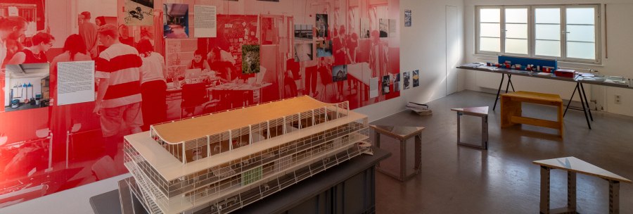 Ausstellung in der Architekturgalerie mit großem Architekturmodell, roten Wandgrafiken, Fotos und Modellen vor einem Fenster., © Thomas Fütterer Ausstellung in der Architekturgalerie mit großem Architekturmodell, roten Wandgrafiken, Fotos und Modellen vor einem Fenster., © Thomas Fütterer