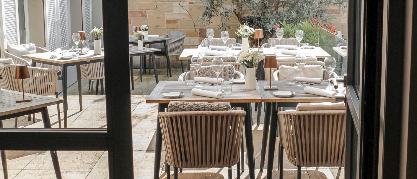 Elegant terrace with laid tables, chairs and plants in the background. The tables are decorated with glasses, plates and flowers., © New Josch, Stuttgart Elegant terrace with laid tables, chairs and plants in the background. The tables are decorated with glasses, plates and flowers., © New Josch, Stuttgart