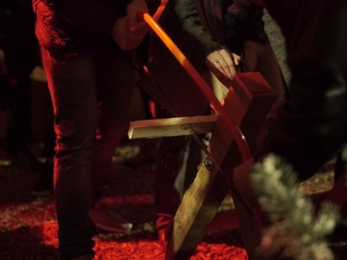 Zwei Personen sägen bei rotem Licht ein Holzbrett mit einer Handsäge. Es ist Teil einer Gruppenaktivität., © Cool-Tours StattReisen Zwei Personen sägen bei rotem Licht ein Holzbrett mit einer Handsäge. Es ist Teil einer Gruppenaktivität., © Cool-Tours StattReisen