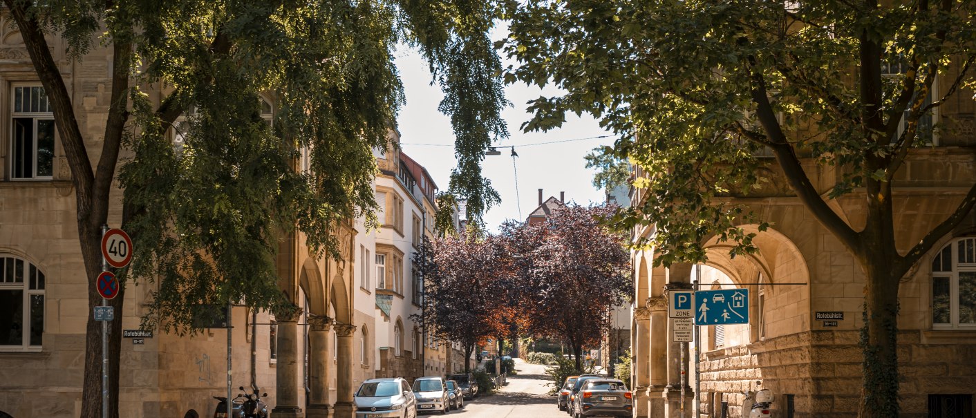 Sonnige Straßenszene mit Bäumen, geparkten Autos und historischen Gebäuden. Verkehrsschilder und ein Gehweg sind sichtbar., © SMG Stuttgart Marketing GmbH - Sarah Schmid Sonnige Straßenszene mit Bäumen, geparkten Autos und historischen Gebäuden. Verkehrsschilder und ein Gehweg sind sichtbar., © SMG Stuttgart Marketing GmbH - Sarah Schmid