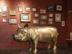 Ein Raum im Schweinemuseum Stuttgart mit einer gro&szlig;en Schweineskulptur und zahlreichen gerahmten Bildern an einer roten Wand., &copy; Stuttgart-Marketing GmbH, Sarah Schmid