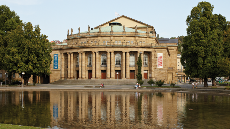 Die Stuttgarter Oper mit ihrer beeindruckenden Fassade spiegelt sich im Wasser des Eckensees wider., © SMG, Christoph Düpper Die Stuttgarter Oper mit ihrer beeindruckenden Fassade spiegelt sich im Wasser des Eckensees wider., © SMG, Christoph Düpper