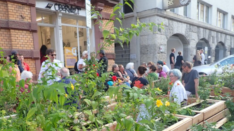 Menschen genießen einen urbanen Garten vor einem Gebäude mit der Aufschrift 'Oberwelt'. Es herrscht eine entspannte Atmosphäre., © Oberwelt e.V. Menschen genießen einen urbanen Garten vor einem Gebäude mit der Aufschrift 'Oberwelt'. Es herrscht eine entspannte Atmosphäre., © Oberwelt e.V.
