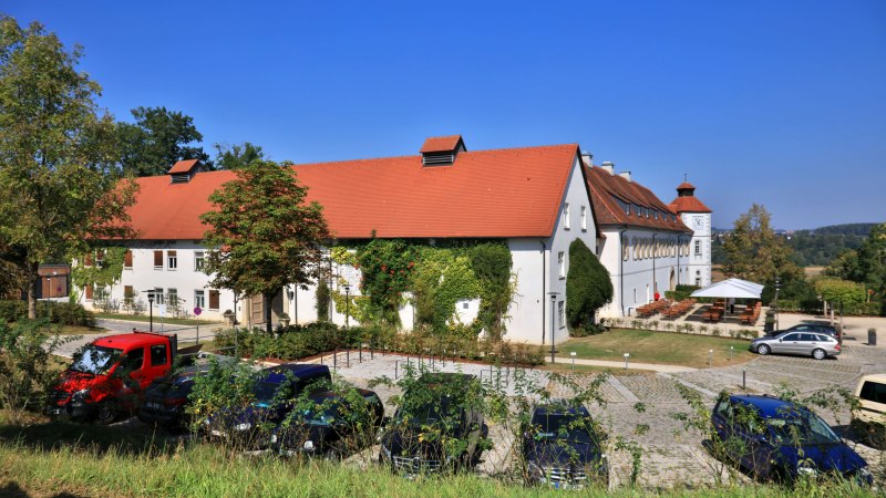 Filseck Castle with a red roof, surrounded by trees. Cars parked in front of it. Blue sky in the background., © Stuttgart-Marketing GmbH, Achim Mende