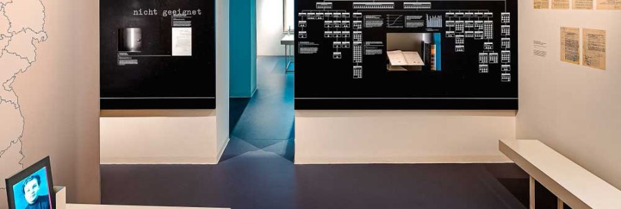 Exhibition room in the Hotel Silber with information boards, documents on the wall and a screen. A table with a map and a passageway are visible., &copy; Haus der Geschichte Baden-W&uuml;rttemberg