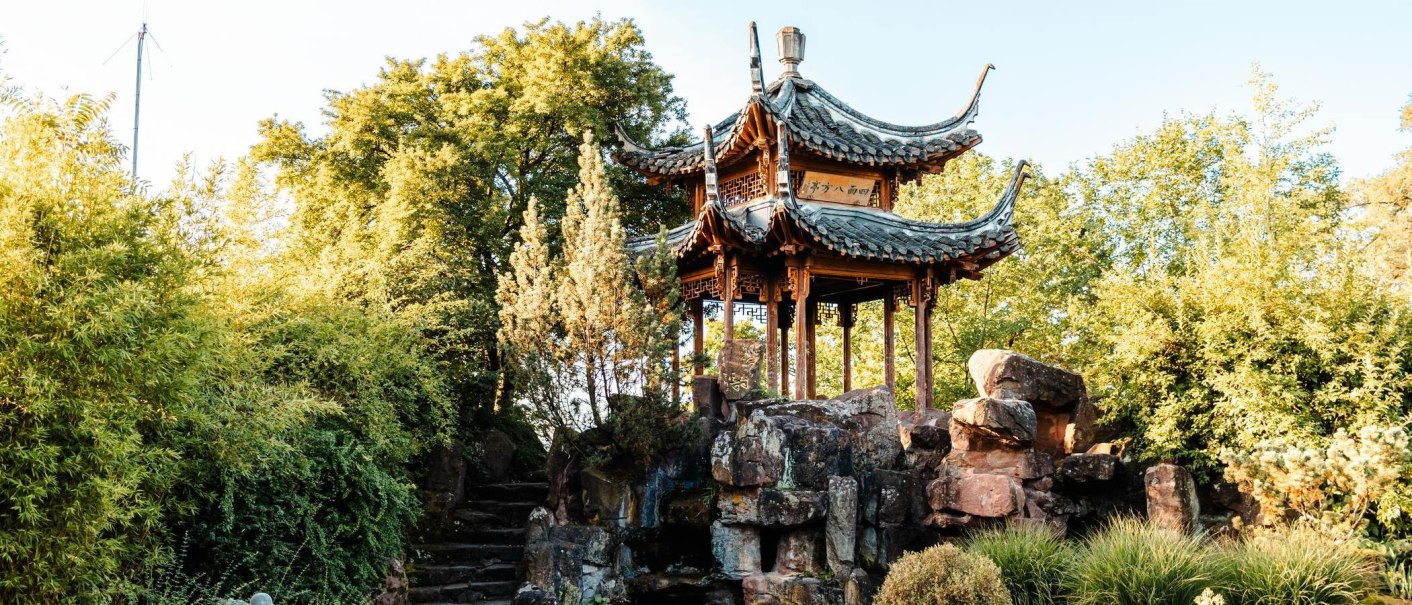 Ein traditioneller chinesischer Pavillon steht auf einem Felsen, umgeben von üppigem Grün im Chinesischen Garten Stuttgart., © Stuttgart-Marketing GmbH, Sarah Schmid Ein traditioneller chinesischer Pavillon steht auf einem Felsen, umgeben von üppigem Grün im Chinesischen Garten Stuttgart., © Stuttgart-Marketing GmbH, Sarah Schmid