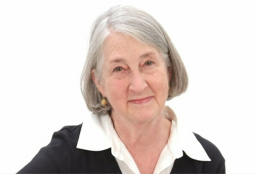 Ältere Frau mit grauem Haar und freundlichem Lächeln, trägt schwarze Kleidung mit weißem Kragen, vor weißem Hintergrund., © IHWA