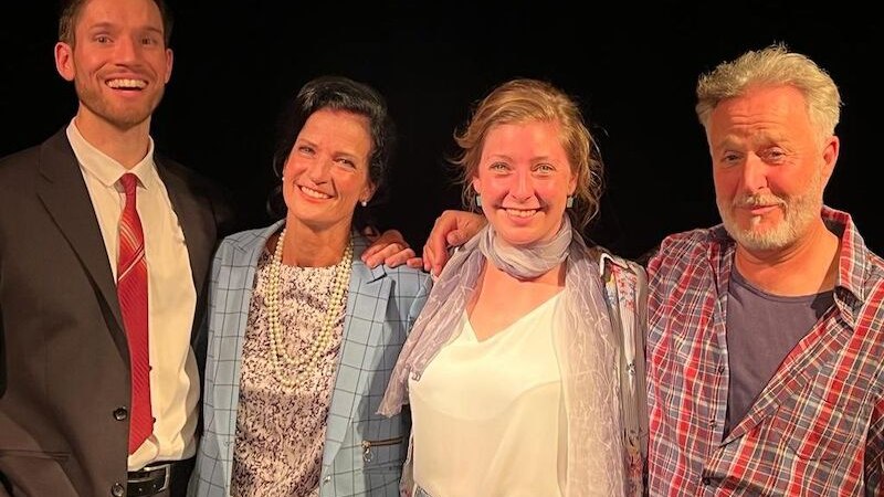 Vier Personen posieren lächelnd nebeneinander, zwei Männer und zwei Frauen, vor einem dunklen Hintergrund. Sie wirken fröhlich und entspannt., © Theater Atelier