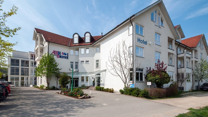 Das Albhotel Fortuna ist ein weißes Gebäude mit rotem Dach, umgeben von Bäumen und einem Parkplatz. Der Himmel ist blau und klar., © Albhotel Fortuna
