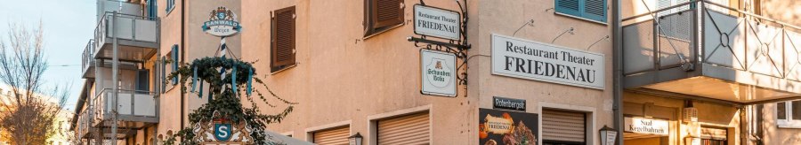 The Restaurant Theater Friedenau shows its facade with several signs and an advertising poster. A beer garden is also visible., © SMG Stuttgart Marketing GmbH - Sarah Schmid The Restaurant Theater Friedenau shows its facade with several signs and an advertising poster. A beer garden is also visible., © SMG Stuttgart Marketing GmbH - Sarah Schmid