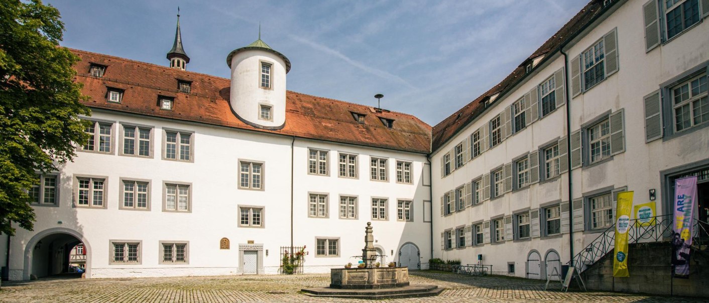 The inner courtyard of Waldenbuch Castle shows white buildings with red roofs and a central fountain. A blue sky completes the scene., © Stuttgart-Marketing GmbH, Sarah Schmid The inner courtyard of Waldenbuch Castle shows white buildings with red roofs and a central fountain. A blue sky completes the scene., © Stuttgart-Marketing GmbH, Sarah Schmid