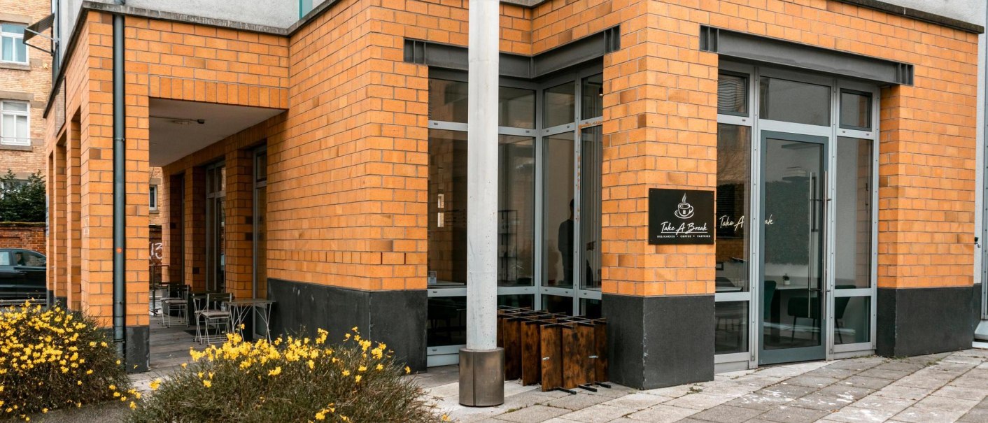 Eingang des Caf&eacute;s mit gelben Backsteinw&auml;nden. Gelbe Blumen im Vordergrund., &copy; Stuttgart-Marketing GmbH, Sarah Schmid