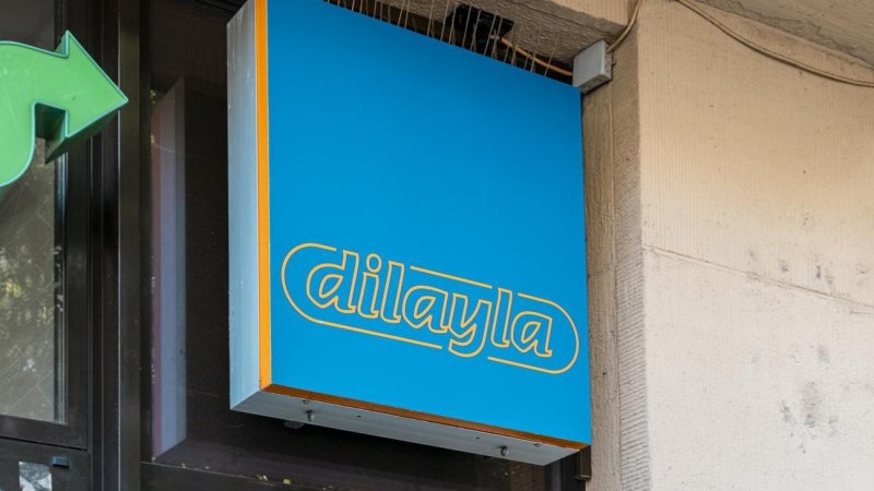 Blaues Schild mit gelber Aufschrift 'dilayla' an einer Gebäudewand, daneben ein grüner Pfeil., © Stuttgart Marketing GmbH, Sarah Schmid