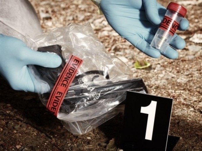 Ein Tatort mit Beweismaterial: Eine Waffe in einer T&uuml;te und ein Beweisr&ouml;hrchen, nummeriert mit 1, werden von einer Person mit Handschuhen untersucht., &copy; Cool-Tours StattReisen