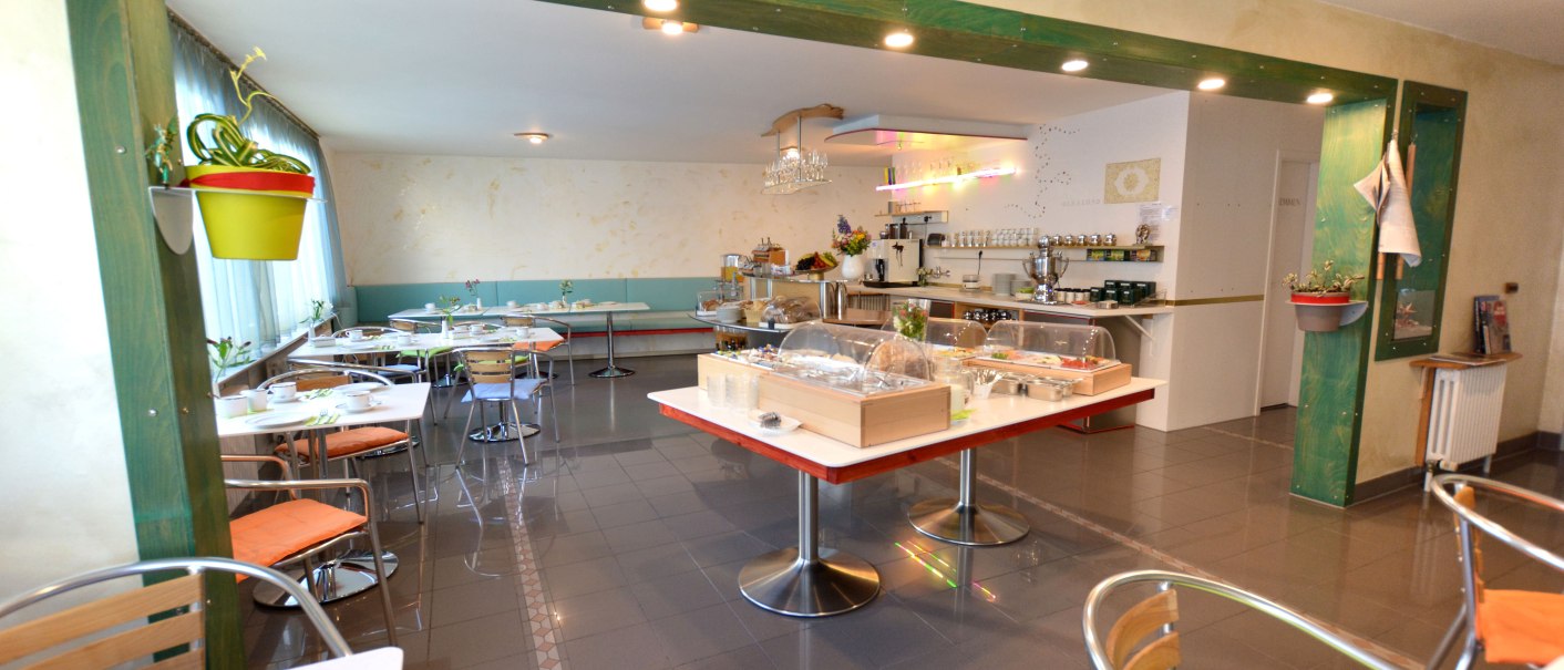 Ein heller Frühstücksraum mit gedeckten Tischen, einem Buffet in der Mitte und Pflanzen an den Wänden. Moderne Einrichtung mit Metallstühlen., © Abalon Hotel Ideal Ein heller Frühstücksraum mit gedeckten Tischen, einem Buffet in der Mitte und Pflanzen an den Wänden. Moderne Einrichtung mit Metallstühlen., © Abalon Hotel Ideal