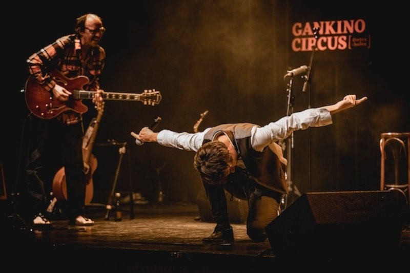 One musician plays the guitar while another bows on stage. A sign with 'Gankino Circus' can be seen in the background., &copy; Renitenztheater Stuttgart e.V.