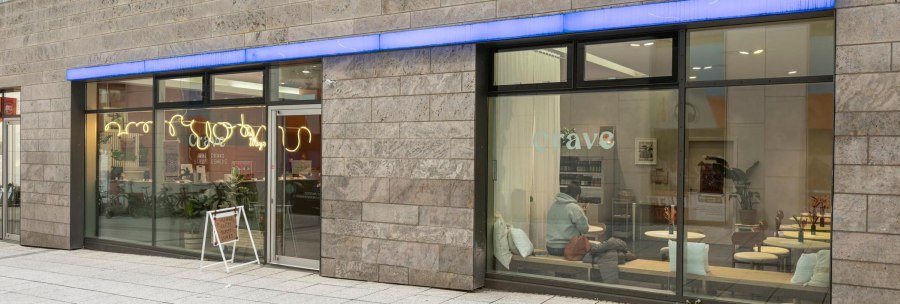 Große Fensterfronten, die Blick auf das Café im Inneren freigeben: Holztische, weiße Kissen., © Stuttgart-Marketing GmbH, Sarah Schmid Große Fensterfronten, die Blick auf das Café im Inneren freigeben: Holztische, weiße Kissen., © Stuttgart-Marketing GmbH, Sarah Schmid