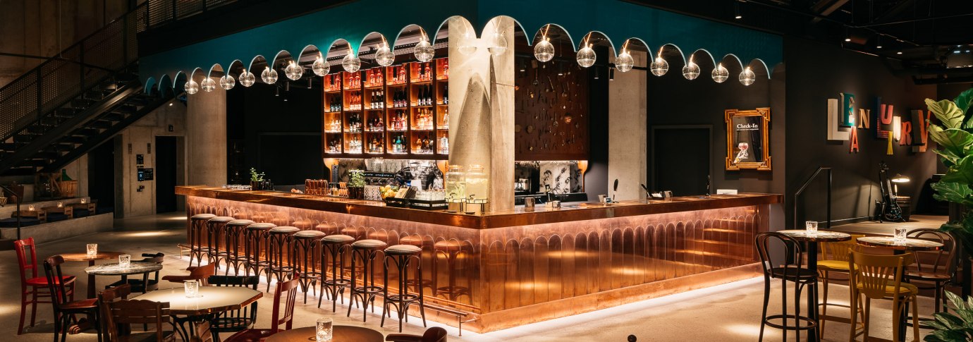 Stilvolle Bar mit Kupfertheke, hängenden Glaskugelleuchten und gemütlichen Sitzbereichen. Moderne Einrichtung mit warmem Licht und dekorativen Elementen., © © Ruby Hotels Stilvolle Bar mit Kupfertheke, hängenden Glaskugelleuchten und gemütlichen Sitzbereichen. Moderne Einrichtung mit warmem Licht und dekorativen Elementen., © © Ruby Hotels