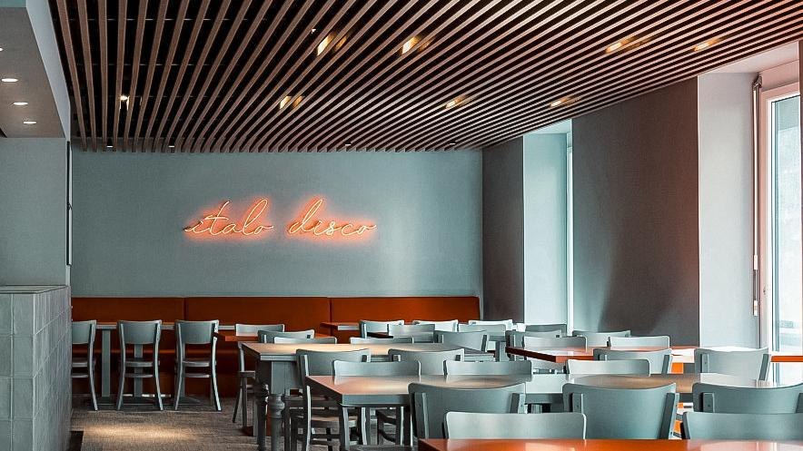 Modernes Restaurant mit grauen Stühlen, Holzgitterdecke und Neon-Schriftzug 'Italo Disco' an der Wand., © Italo Disco, Stuttgart Modernes Restaurant mit grauen Stühlen, Holzgitterdecke und Neon-Schriftzug 'Italo Disco' an der Wand., © Italo Disco, Stuttgart