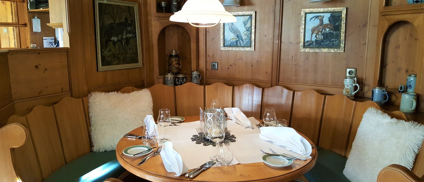 Gemütliche Holzecke mit rundem Tisch, gedeckt mit Gläsern und Servietten. An den Wänden hängen Bilder, dekoriert mit Kissen und Krügen., © Erikson Hotel Gemütliche Holzecke mit rundem Tisch, gedeckt mit Gläsern und Servietten. An den Wänden hängen Bilder, dekoriert mit Kissen und Krügen., © Erikson Hotel