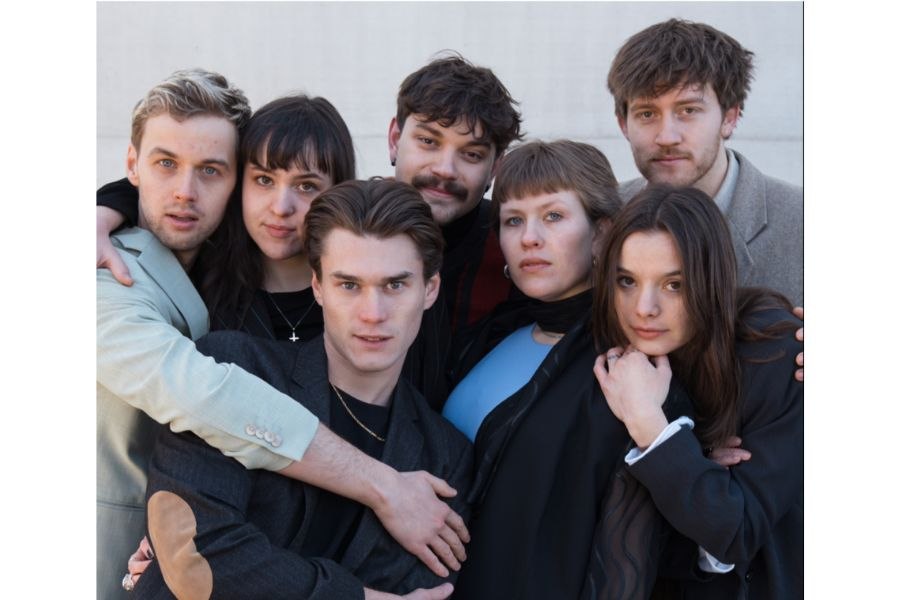 Sieben junge Erwachsene posieren eng umschlungen vor einer neutralen Wand. Sie tragen verschiedene stilvolle Outfits., © HMDK Stuttgart