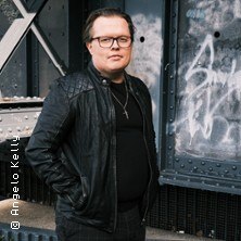Person in a black leather jacket stands in front of a wall with graffiti., &copy; links im Bild